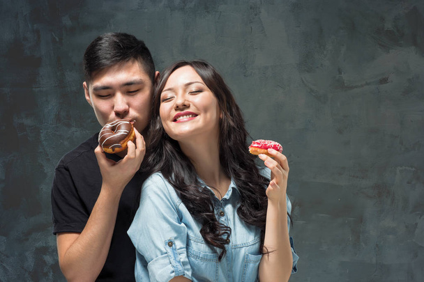 Young asian couple enjoy eating of sweet colorful donut - Foto, Imagem