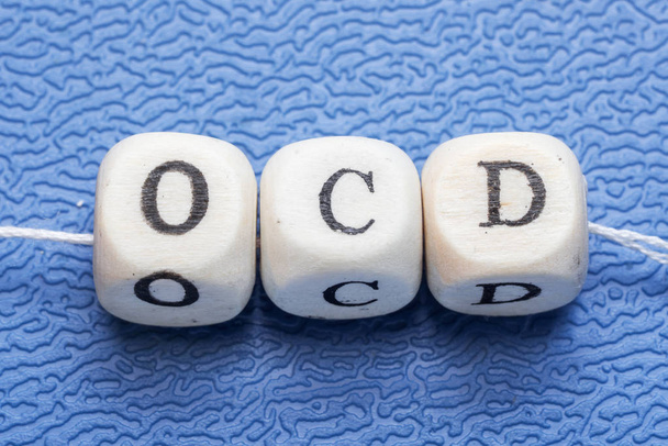 A Word ocd (kényszerbetegségben szenvedő) egy fából készült kocka kék háttérrel - Fotó, kép