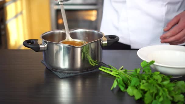 σεφ χύνοντας σούπα σε ένα πιάτο και διακοσμεί με βότανα - Πλάνα, βίντεο