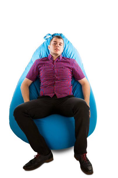 Young man sitting on blue beanbag  - Foto, afbeelding