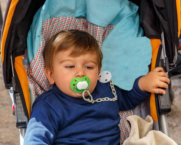 Een jongen met een fopspeen in zijn kinderwagen - Foto, afbeelding