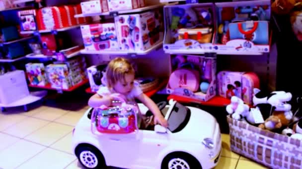Söpö kaksivuotinen tyttö opiskelee leluautoa kaupassa
 - Materiaali, video