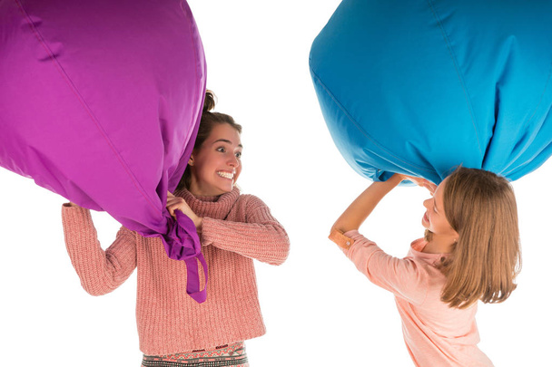 Young funny laughing girls fighting with beanbag chairs - Fotoğraf, Görsel