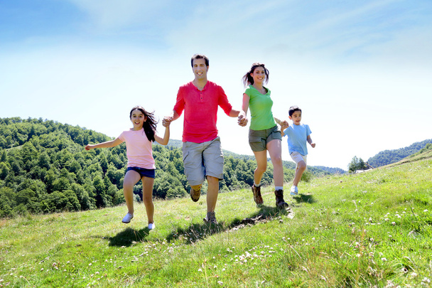 Happy family enjoying and running together in the mountains - Фото, изображение