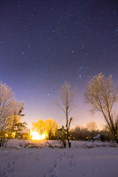 Ciel plein d'étoiles au-dessus d'un village d'hiver enneigé
 - Photo, image