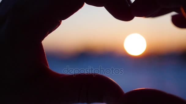 κορίτσι κάνει καρδιά με τα χέρια στον ήλιο. Σιλουέτα χέρι σε σχήμα καρδιάς με μέσα στο ηλιοβασίλεμα. Χειμώνας - Πλάνα, βίντεο