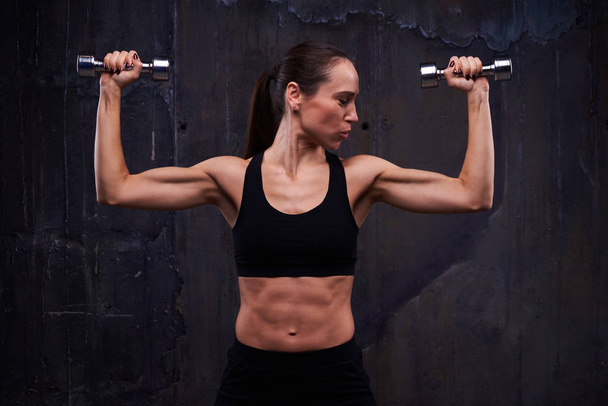Strength workout of muscular confident female doing biceps curl  - Foto, immagini