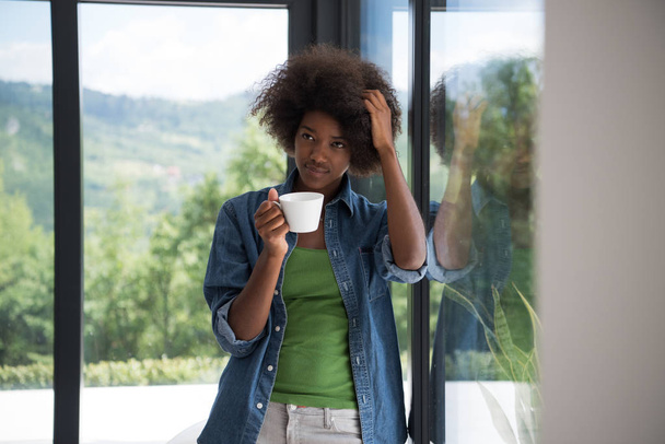 African American woman drinking coffee looking out the window - Photo, image