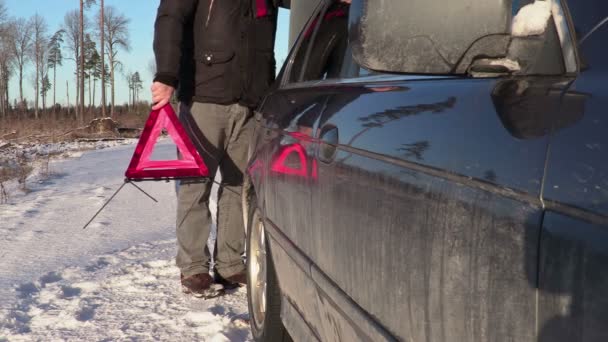 Muž s výstražným trojúhelníkem pěší poblíž auto v zimě  - Záběry, video