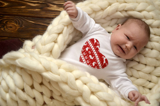 kleines Kind in einer Decke aus dickem Garn. Weihnachtsthema. fröhlicher Valentinstag - Foto, Bild