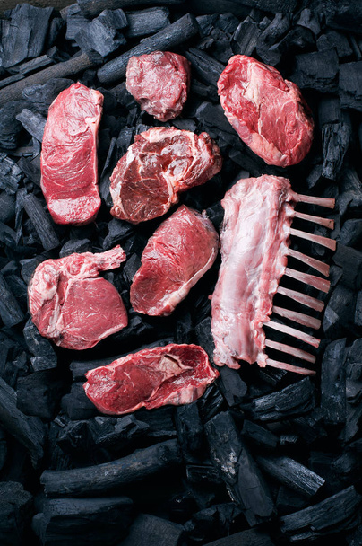 Carne cruda al carbone. Varietà di bistecche. Fondo con carbone di legna
. - Foto, immagini
