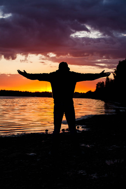 Silueta del hombre levantando sus manos o brazos abiertos cuando sale el sol
 - Foto, imagen