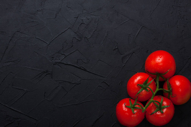 Punainen tuoreet orgaaniset tomaatit mustalla betonitaustalla
 - Valokuva, kuva