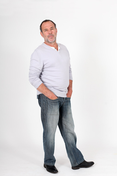Senior man standing on white background with hands in pocket - Foto, imagen