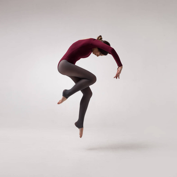 young woman dancer in maroon swimsuit jumping - Foto, immagini