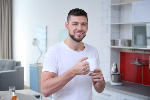 Handsome young man drinking coffee at home - Фото, зображення