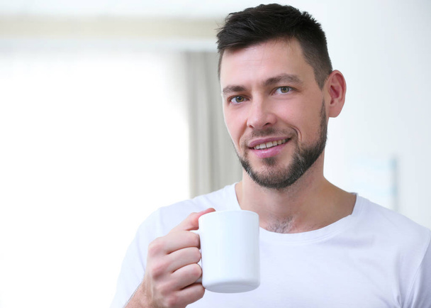 Handsome young man drinking coffee at home - Fotó, kép