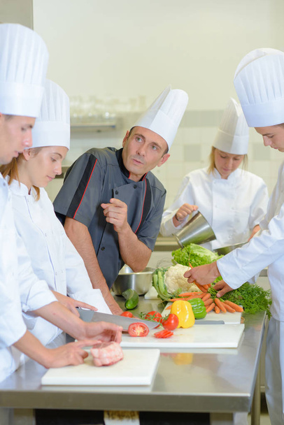 Chef instructing trainee caterers - Фото, изображение