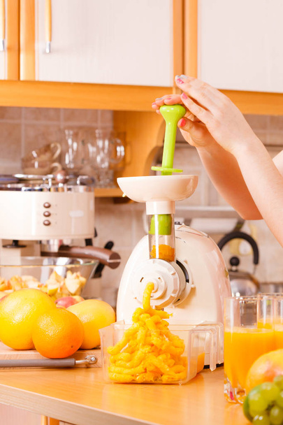 Woman making orange juice in juicer machine  - Fotografie, Obrázek