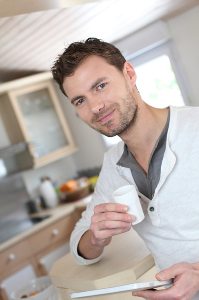 Young man using electronic tablet while drinking coffee - Foto, afbeelding