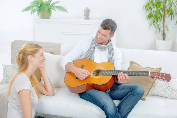 Trying to impress his girlfriend by playing guitar - Zdjęcie, obraz
