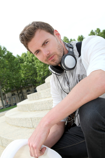 Portrait of guy with music headphones sitting in town - Фото, изображение
