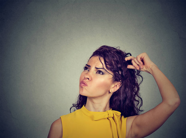 Confused thinking woman bewildered scratching her head seeks solution  - 写真・画像