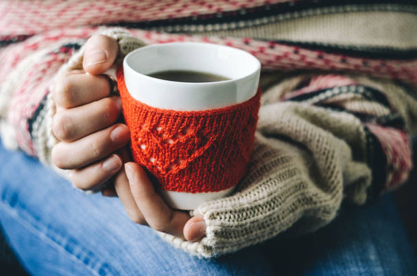 Red Knitted woolen cup with heart pattern in female hands. - Valokuva, kuva