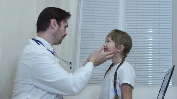 Παιδική γιατρός φαίνεται στο λαιμό του παιδιού στο γραφείο, ο γιατρός εξετάζει το κορίτσι στο γραφείο. - Πλάνα, βίντεο