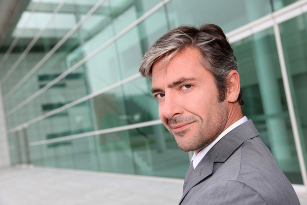 Portrait of businessman standing in front of modern building - Фото, зображення