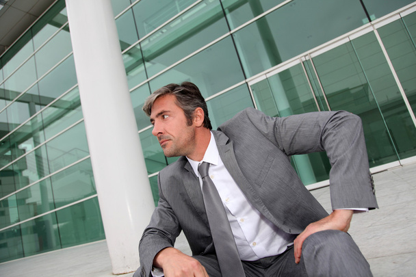 Businessman sitting in stairs in front of building - Foto, Bild
