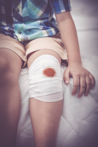 Child injured. Wound on the child's knee with bandage. Vintage tone effect. - Фото, зображення