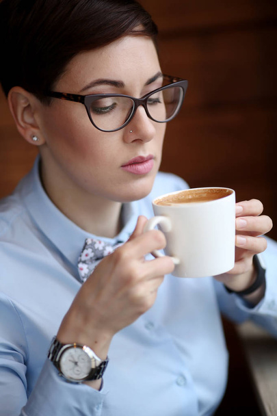 Young beautiful woman, office worker in glasses, went to the cafe for a coffee break, laynch, drinking coffee  - Foto, immagini