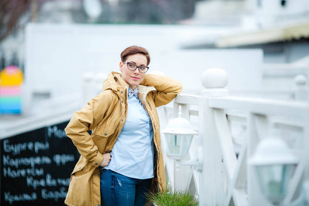 Young beautiful woman  in glasses, short fashionable hairstylein in office clothes, jacket, walking through the streets, spring walks - Photo, Image