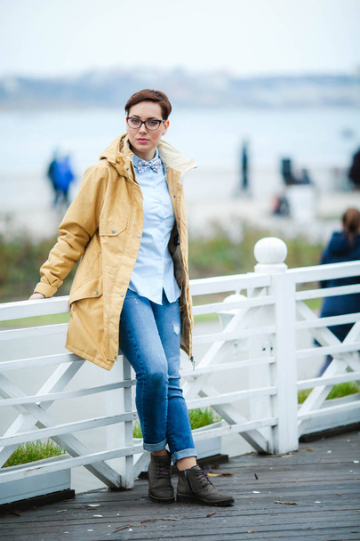 Young beautiful woman  in glasses, short fashionable hairstylein in office clothes, jacket, walking through the streets, spring walks - Zdjęcie, obraz