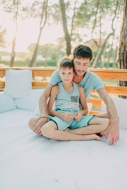 Son with his father on a wooden couch - Фото, зображення