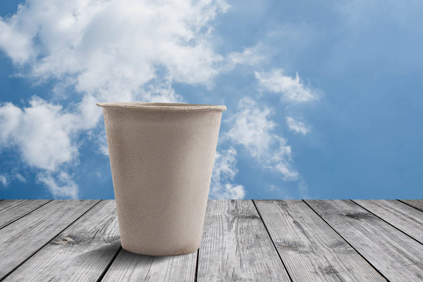 Чашка кави на дерев'яному столі з фоном блакитного неба
  - Фото, зображення