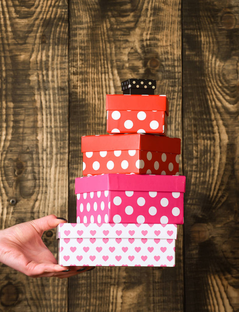 colorful spotted present box in female hand on wooden background - Foto, imagen