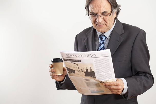 Businessman reading newspaper on gray background - Photo, Image