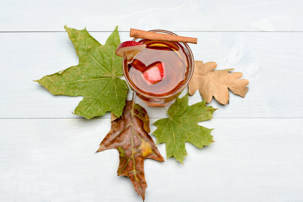 glass with juice, pieces of apple, cinnamon, leaves - 写真・画像