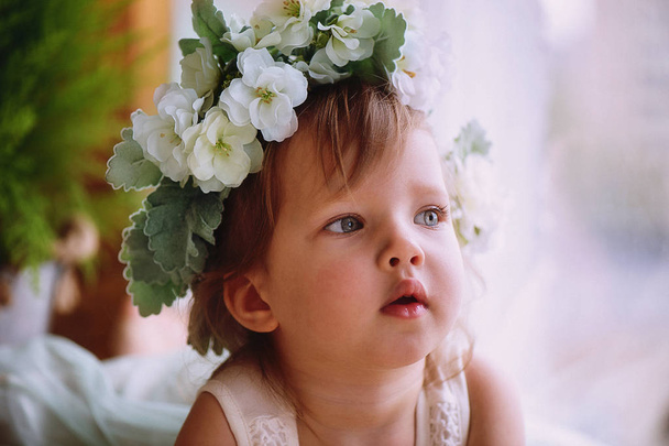 Beautiful little girl in a wreath on the head in green and white. Party dress,  Princess. - Photo, Image