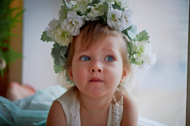 Beautiful little girl in a wreath on the head in green and white. Party dress,  Princess. - Valokuva, kuva