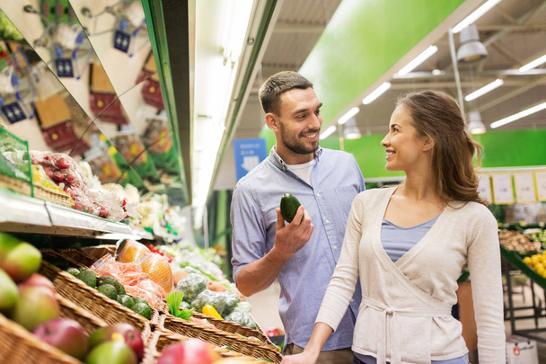 happy couple buying avocado at grocery store - Zdjęcie, obraz