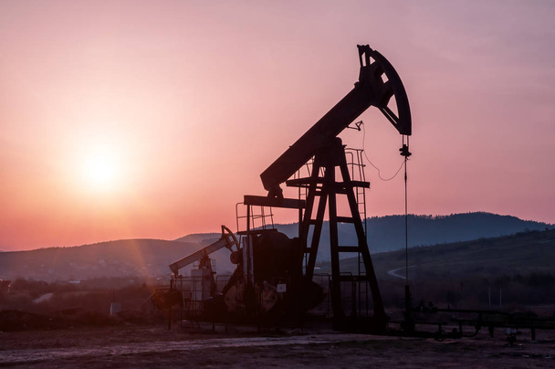 silueta olejové pumpy na krásném červeném západu slunce - Fotografie, Obrázek