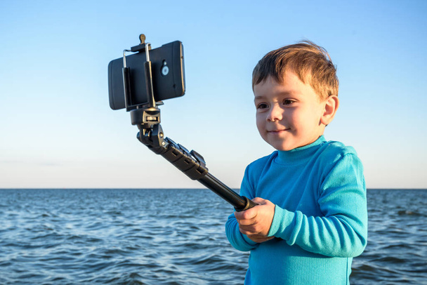 Young boy doing a selfie at the beach, kid happy and smiling loo - Photo, Image