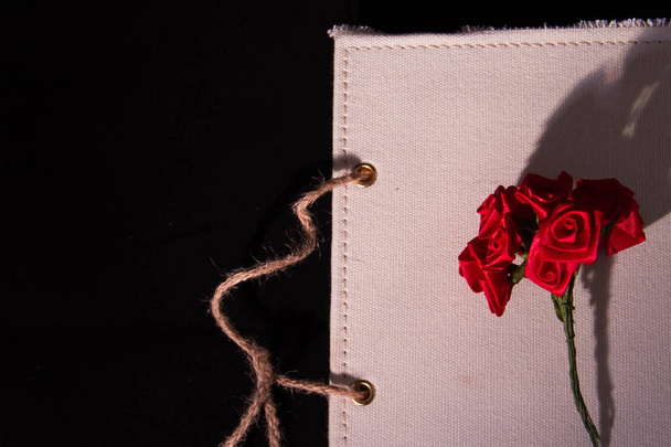 Červená stuha růže na bílé textilní v tmavém pozadí - Fotografie, Obrázek