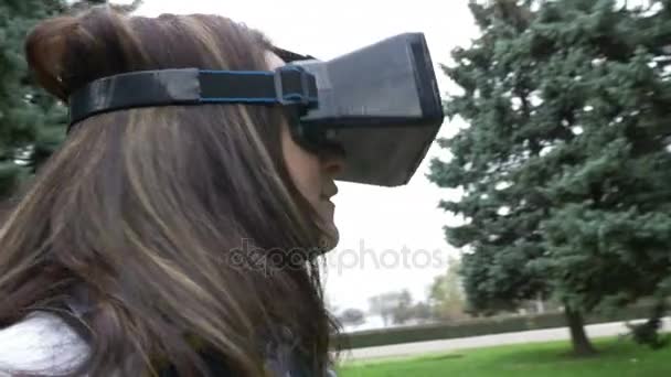 Woman looking around in park using VR 3d headset - Imágenes, Vídeo