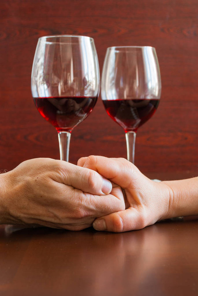 Two glasses of wine on a wooden table.  Hands. - Foto, immagini