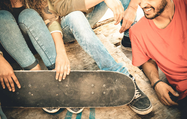Grupo de amigos multirraciales que se divierten y pasan tiempo juntos en el skate board park - Concepto de amistad juvenil con jóvenes que comparten skate al aire libre - Filtro retro desaturado vintage
 - Foto, imagen