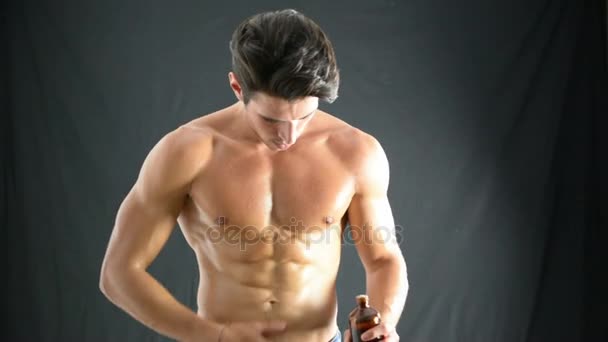 muskulöser junger Mann, der Öl auf seine Haut aufträgt - Filmmaterial, Video